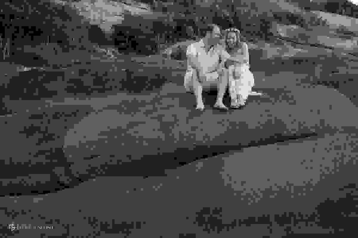 casal rindo em cima da pedra na praia da Barra da Lagoa