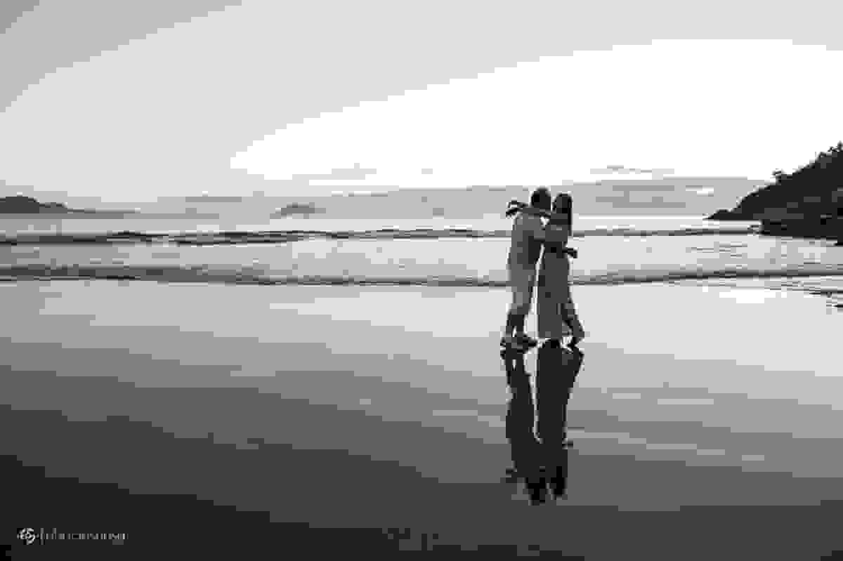 espelho d'água na areia da praia com casal se beijando