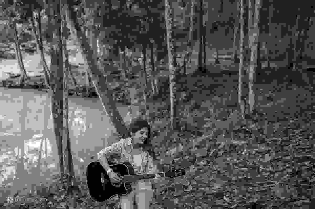 Aniversariante toca violão em meio a natureza do parque