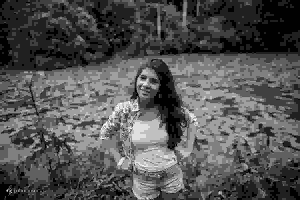 Juliana com as mãos na cintura em frente ao lago cheio de vitórias régias