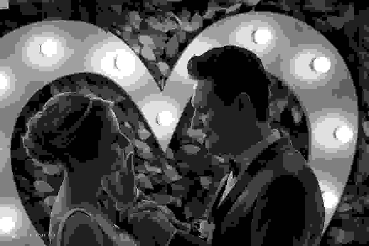 carícias dos noivos com luzes de coração no fundo