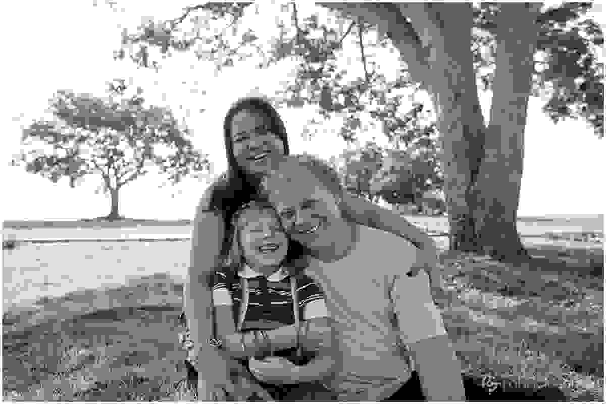 Pai, mãe e filha reunidos na sombra da árvore