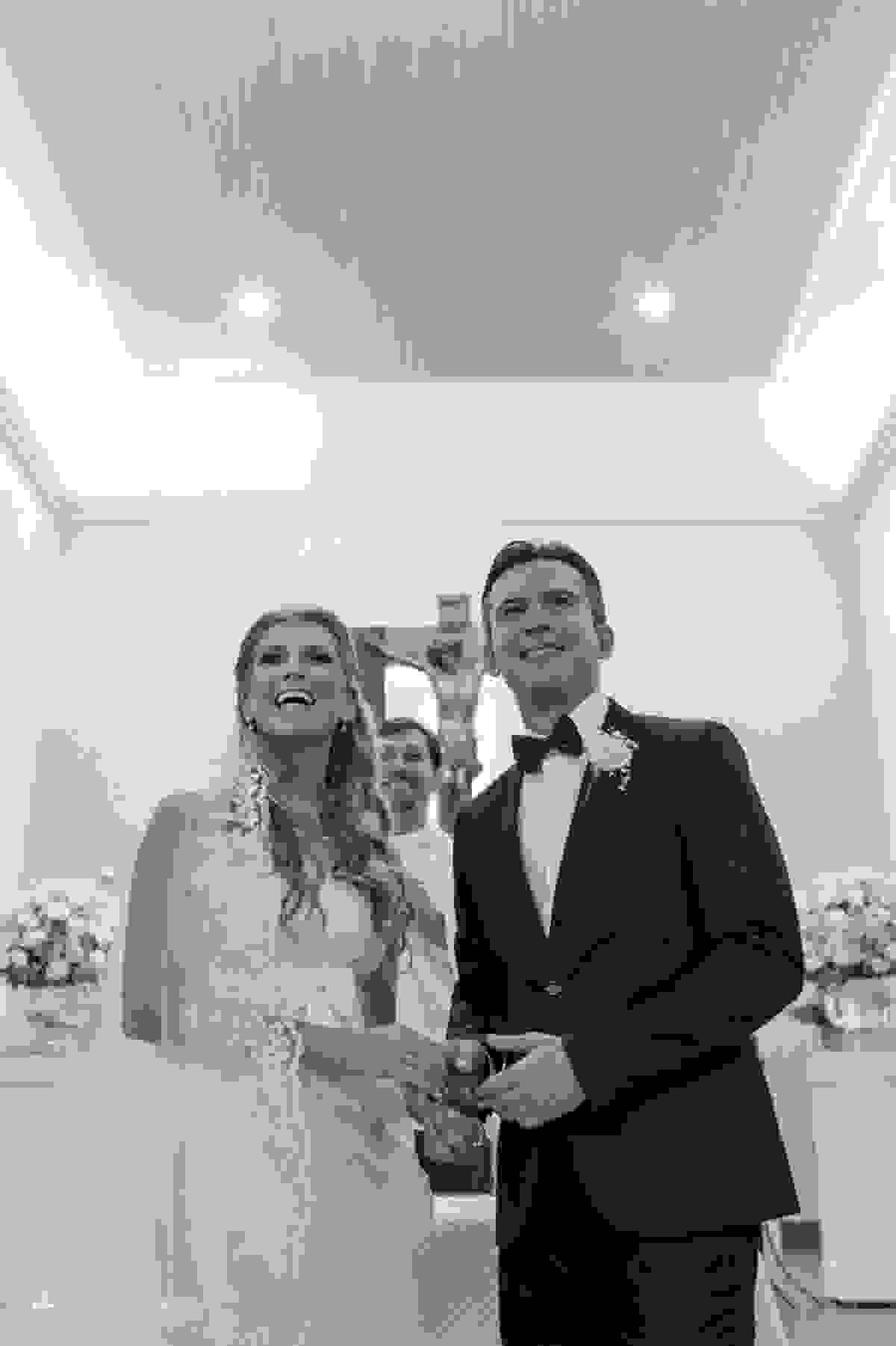 Casal de noivos no altar sorriem para os convidados presentes na igreja