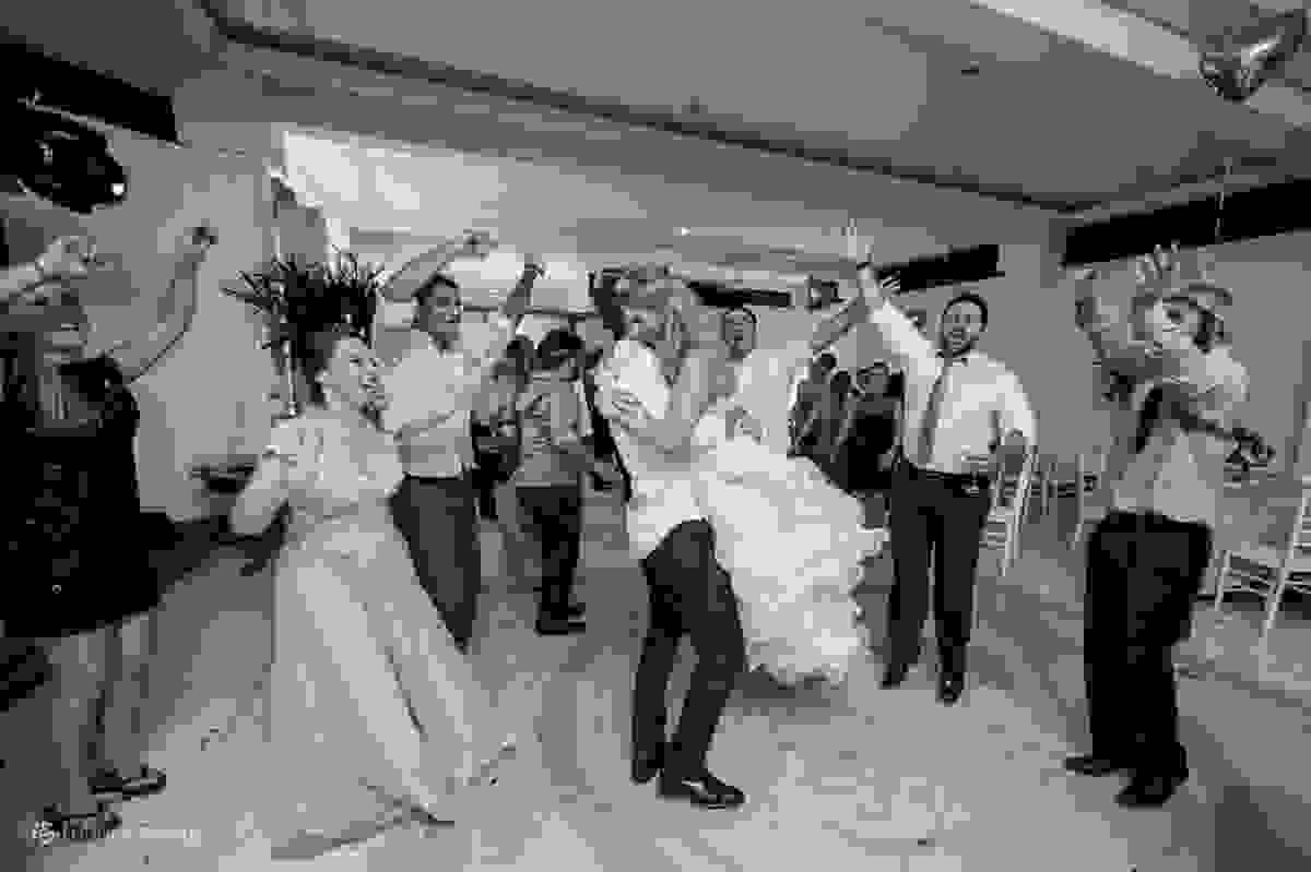 Noivo abraça e gira a noiva durante a festa de cerimônia na pista de dança com amigos em volta