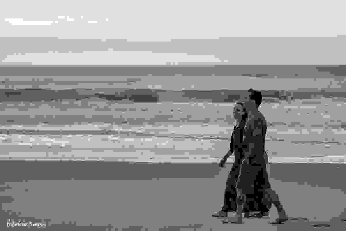 casal caminhando na areia da praia